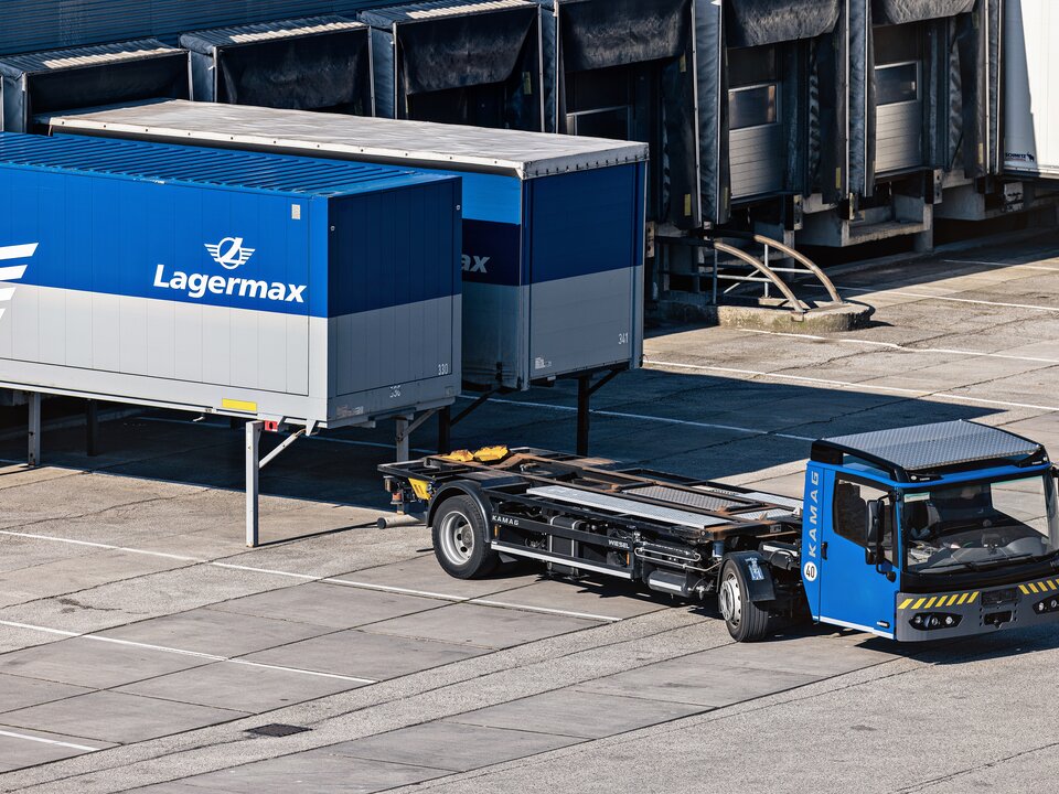 Ein Sattelzug faehrt vor zwei Lasten mit Lagermax Logo