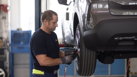 Lagermax-Mitarbeiter bei der Montage von Autoreifen. 