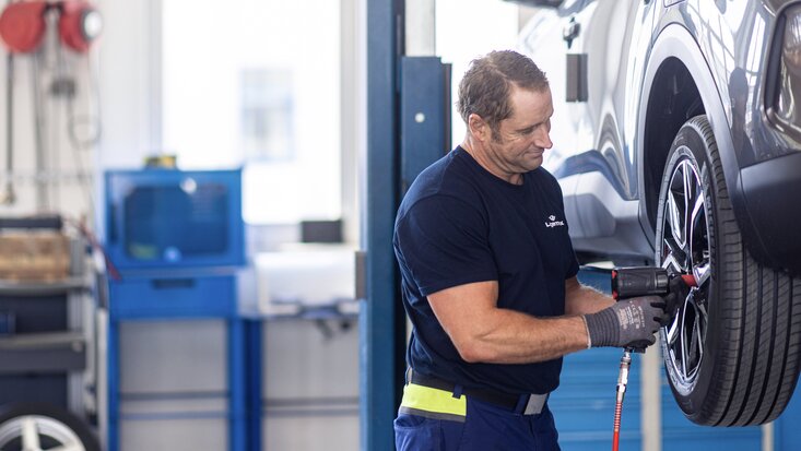 Mann montiert Reifen Schlagbohrer