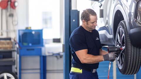 Mann montiert Reifen Schlagbohrer