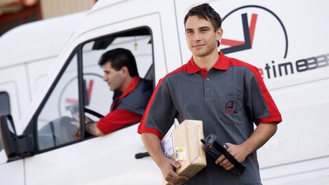 Mann mit Paket und Scanner vor Lkw Nahaufnahme.