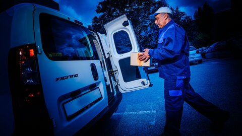 Mann lädt Paket in Transporter Nachtaufnahme.
