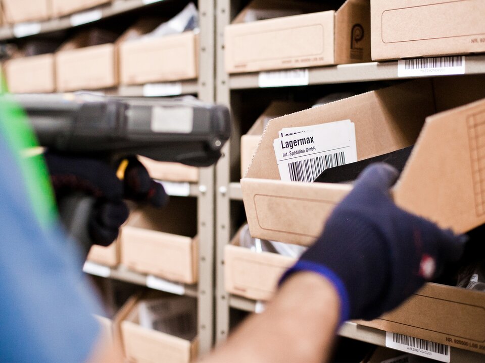 Mann scannt Kleinteile in Regallager Nahaufnahme.