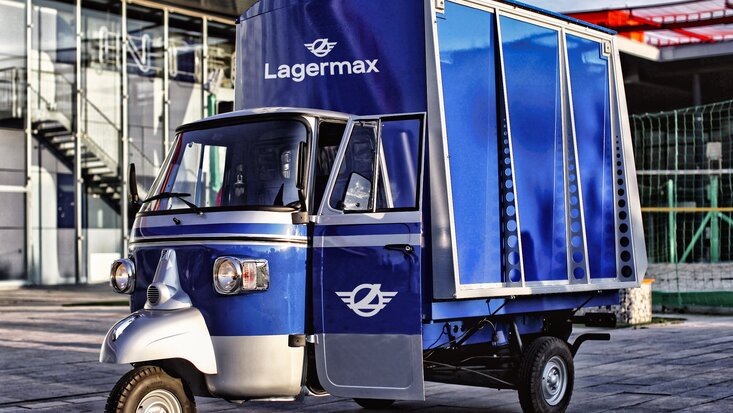 Ape Classic in blau steht vor Gebäude.