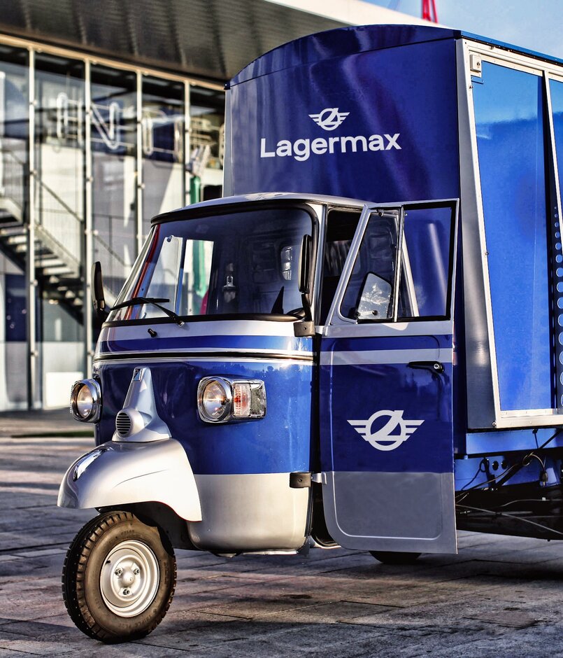 Ape Classic in blau steht vor Gebäude.