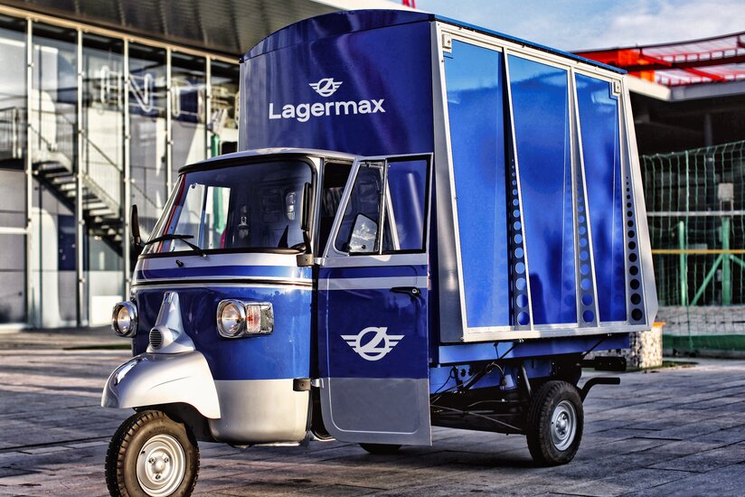 Ape Classic in blau steht vor Gebäude.