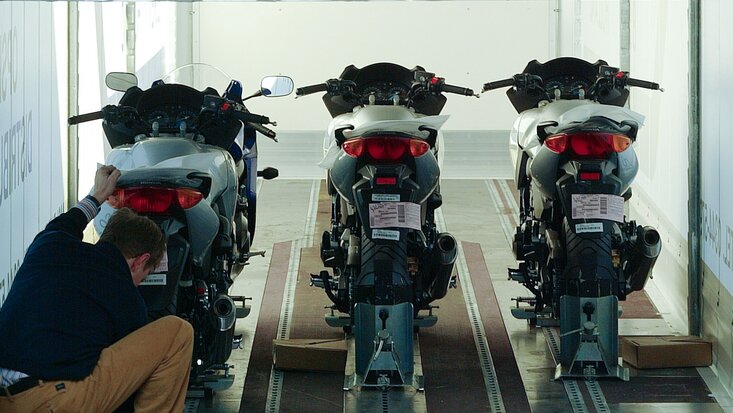 Man sieht einen Lagermax Mitarbeiter beim Verladen von Motorrädern in einen Transport LKW