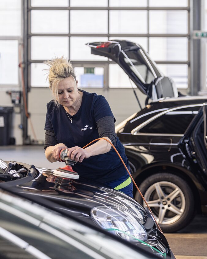Frau poliert Motorhaube Lagermax Hochformat 