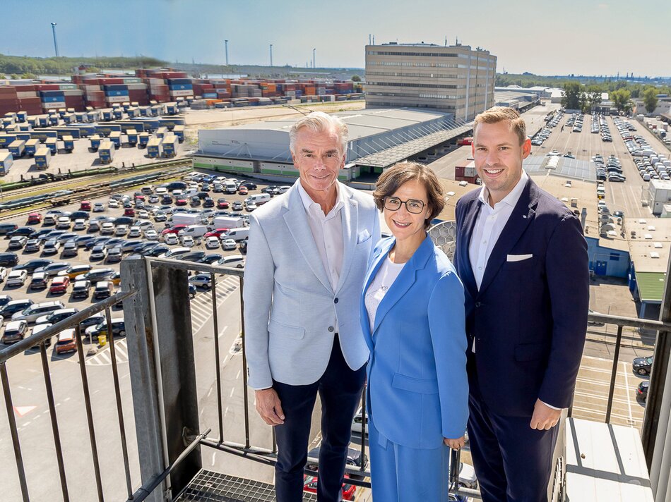 Gruppenbild - Dame mit zwei Herren auf Balkon mit Fahrzeugparkplatz im Hintergrund