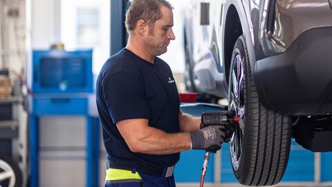 Bei der Reifenmontage sieht man einen Arbeiter mit Werkzeug