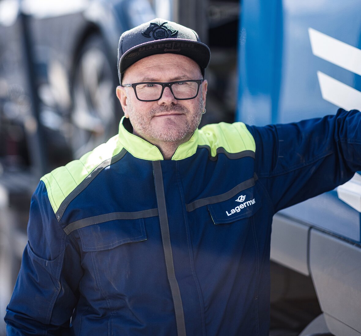 Ein Portrait eines Arbeiters der sich an einen LKW lehnt