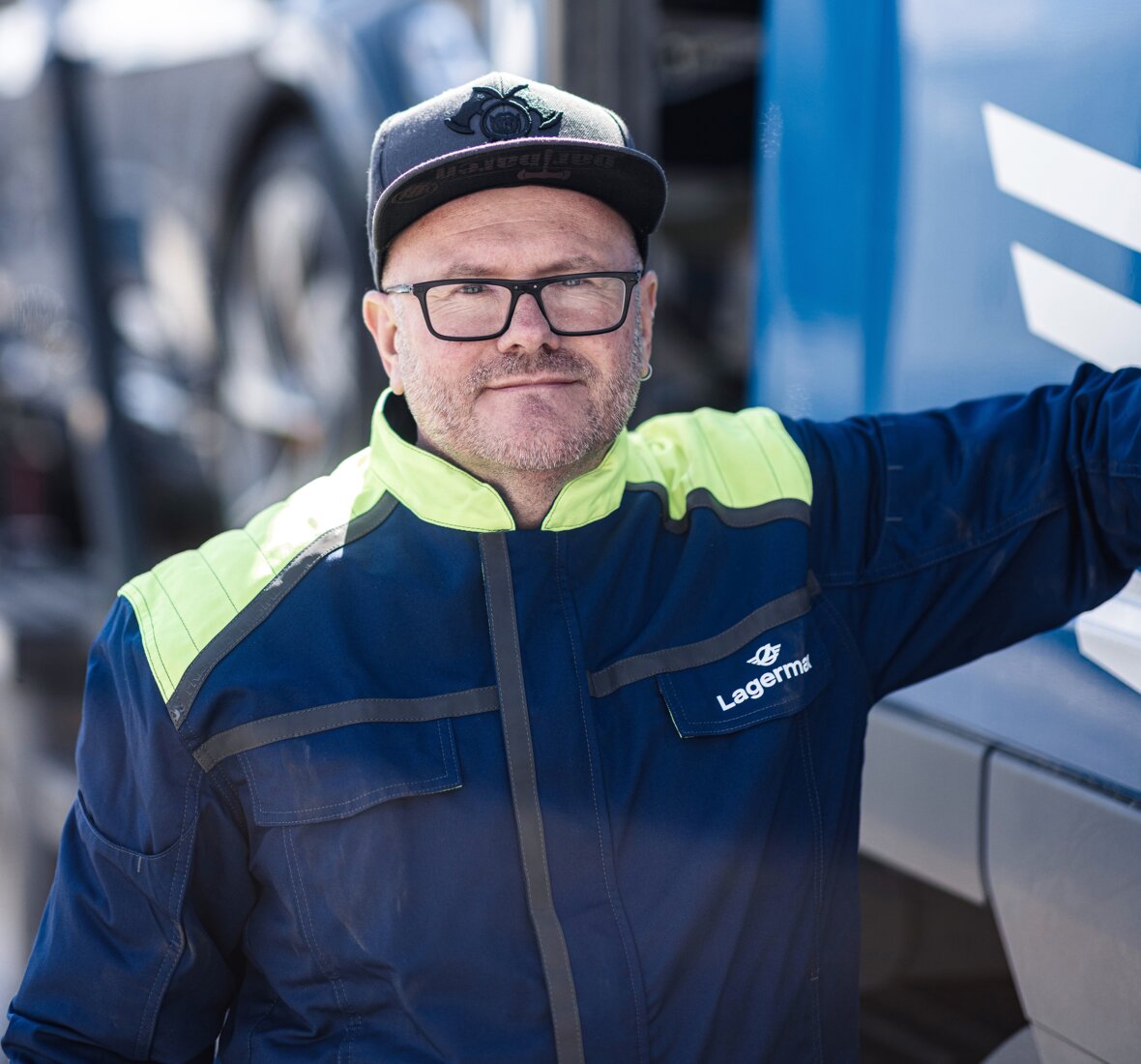 Ein Portrait eines Arbeiters der sich an einen LKW lehnt