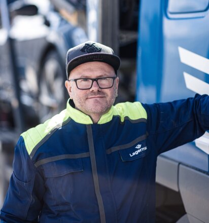 Ein Portrait eines Arbeiters der sich an einen LKW lehnt