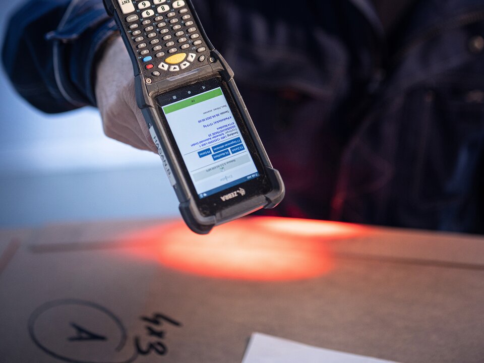 Ein Arbeiter scannt mit einem digitalen Geraet ein Paket