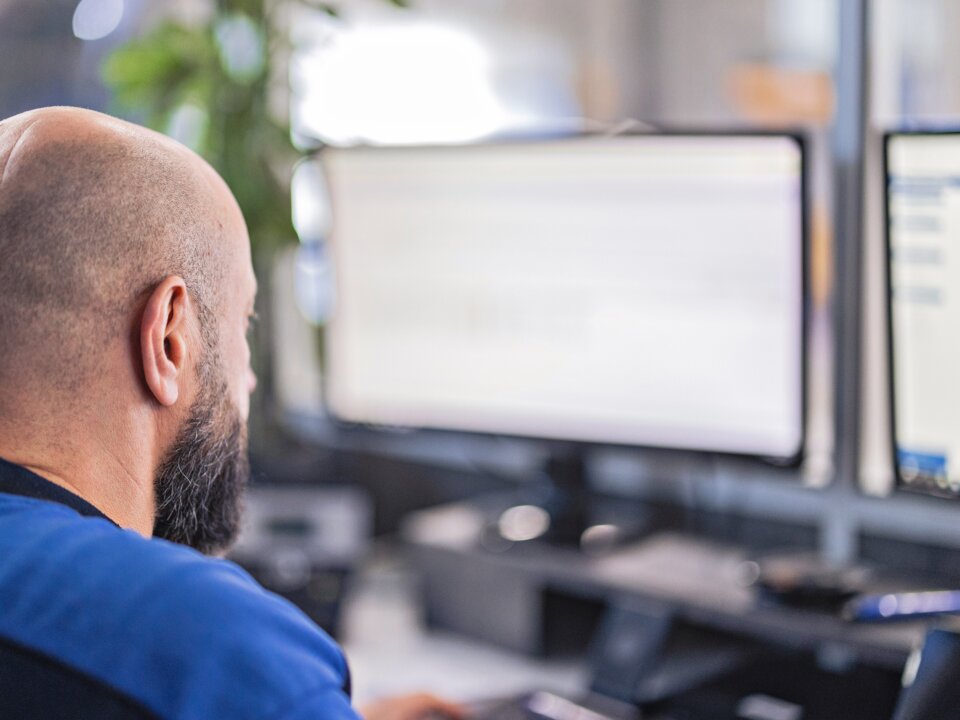 Das ist eine Nahaufnahme von hinten von einem Arbeiter im Buero