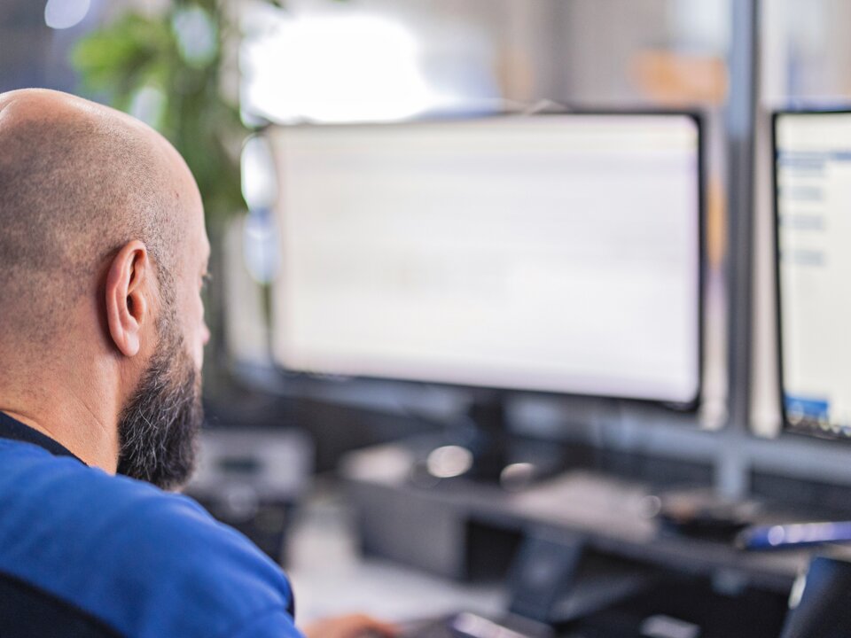 Das ist eine Nahaufnahme von hinten von einem Arbeiter im Buero