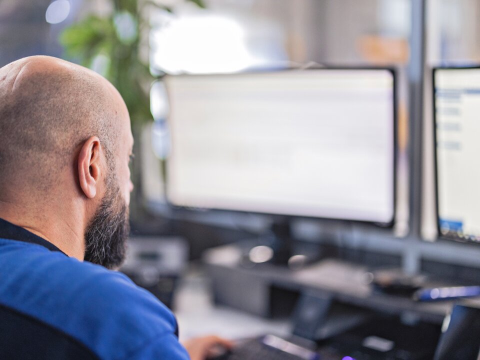 Das ist eine Nahaufnahme von hinten von einem Arbeiter im Buero