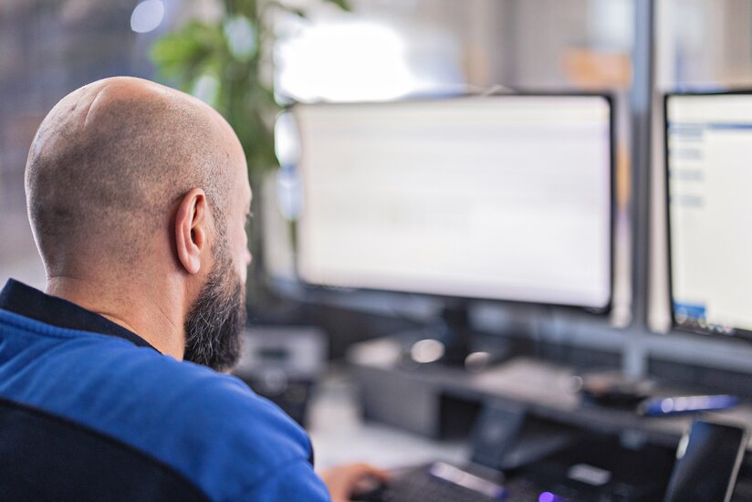 Das ist eine Nahaufnahme von hinten von einem Arbeiter im Buero