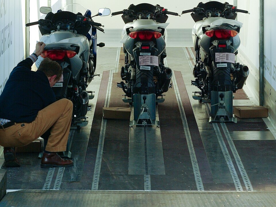 Lagermax Motorad Transport und Logistik Man sieht einen Lagermax Mitarbeiter beim Verladen von Motorrädern in einen Transport LKW