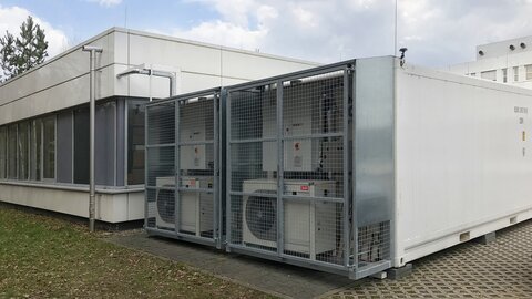 Kühlcontainer von hinten neben Gebäude.