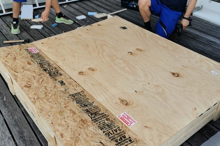 Mitarbeiter verpacken Gemälde in Holzkiste.