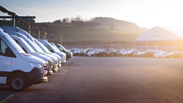 Parkplatz bei Sonnenaufgang mit Fokus links auf Arbeitsfahrzeugen von Lagermax.
