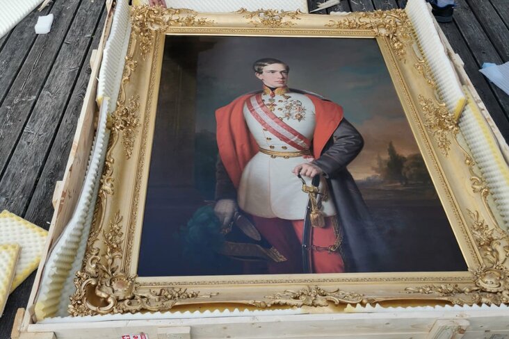 Mann verpackt Gemälde in Holzkiste.