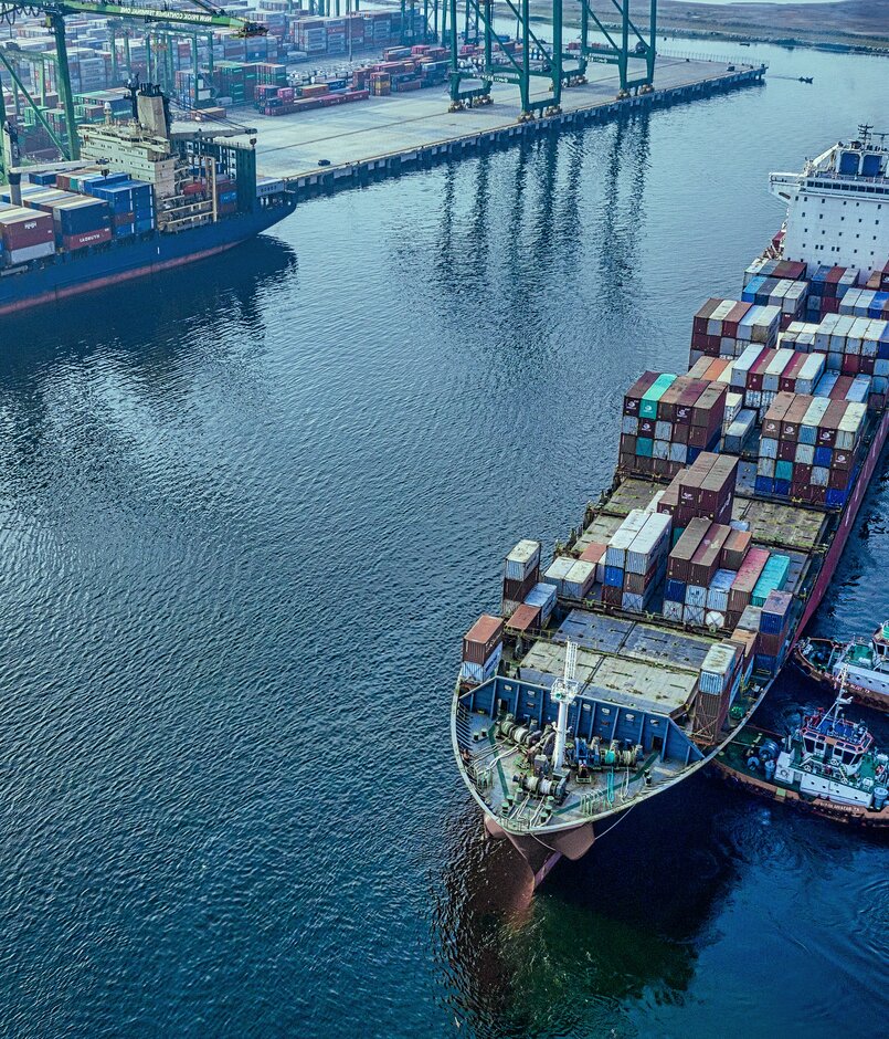 Containerschiff wird von zwei Schleppern zur Liegeposition im Hafen gebracht.