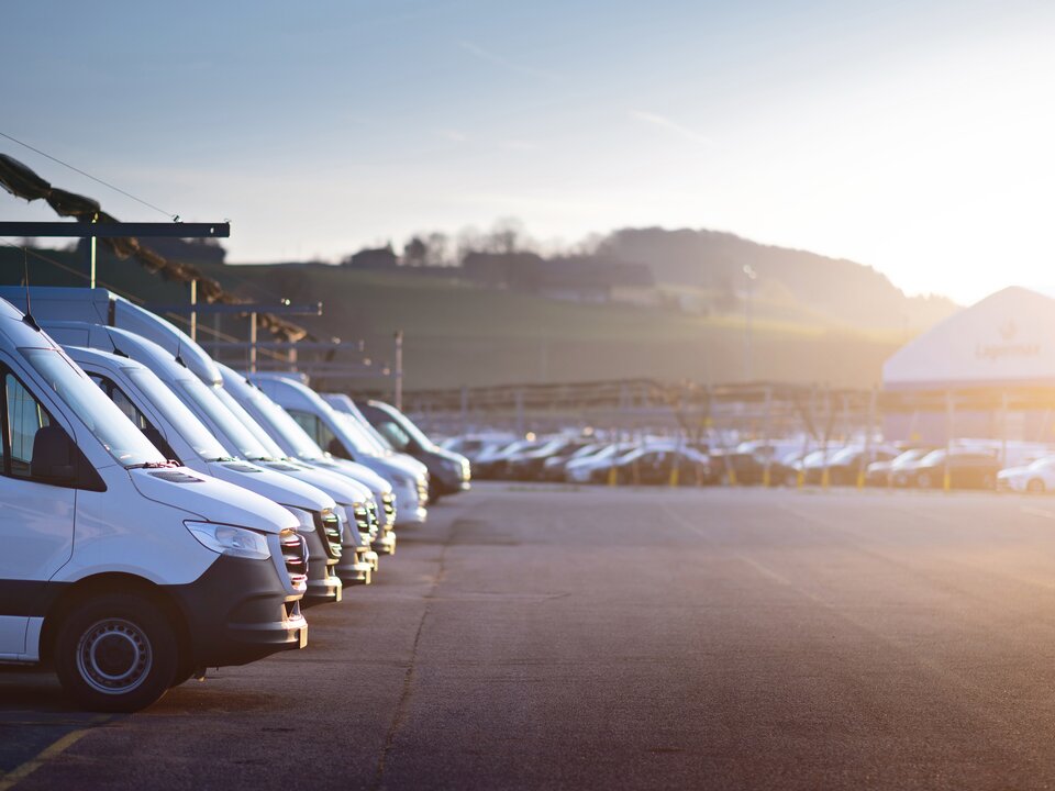 Parkplatz bei Sonnenaufgang mit Fokus links auf Arbeitsfahrzeugen von Lagermax.