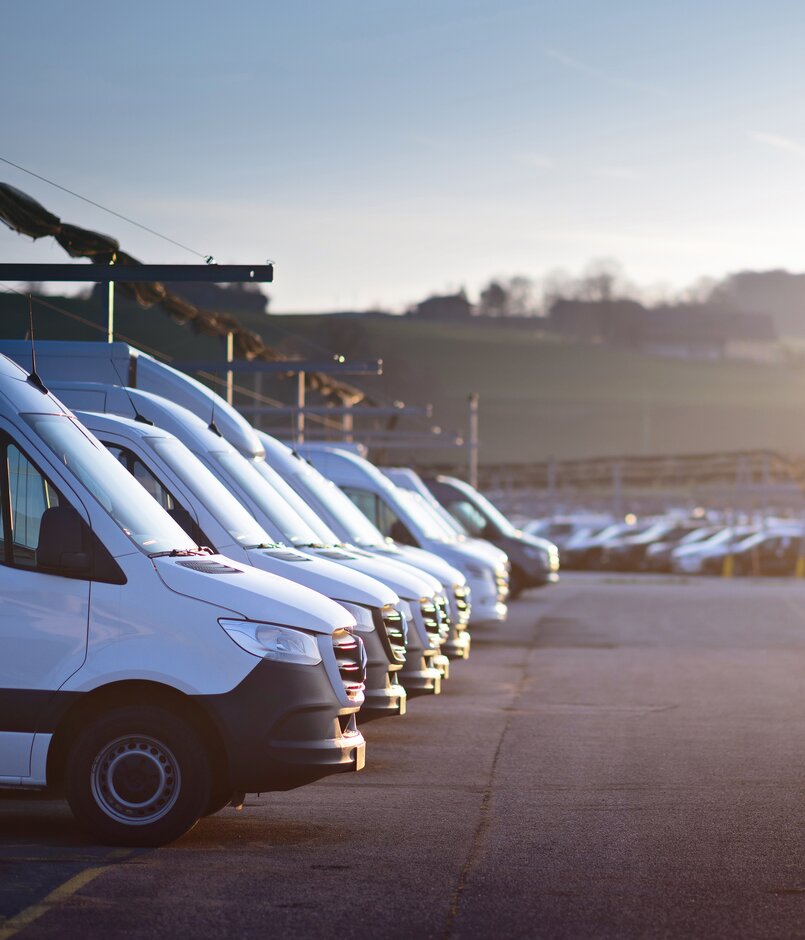 Parkplatz bei Sonnenaufgang mit Fokus links auf Arbeitsfahrzeugen von Lagermax.