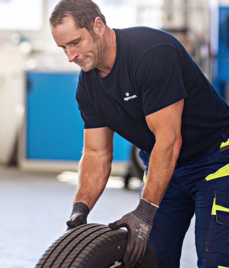 Ein Arbeiter greift einen Autoreifen im Hochformat