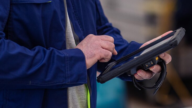 Ein Portrait von einem Lagermax Mitarbeiter mit einem Tablet im Hochformat
