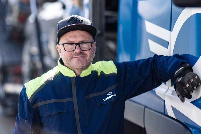 Man sieht ein Portrait eines Arbeiters der sich an einen LKW lehnt