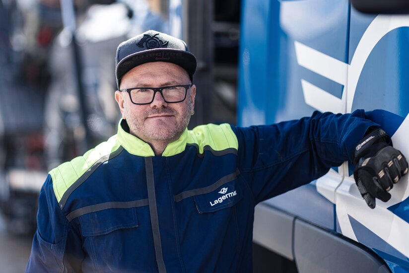 Man sieht ein Portrait eines Arbeiters der sich an einen LKW lehnt