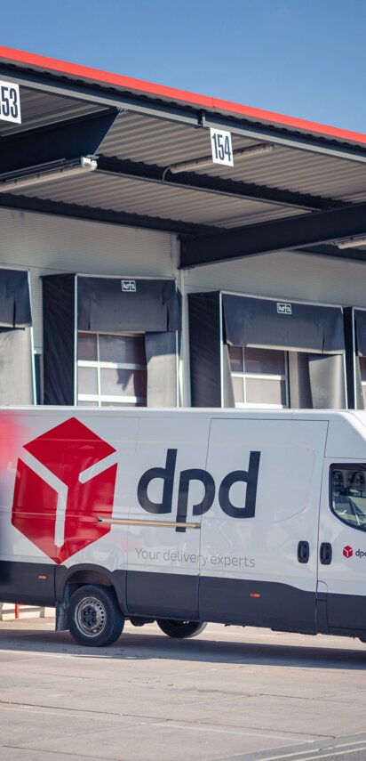 Es steht ein dpd Transporter vor einer Lagerhalle und wird mit Paketen beladen