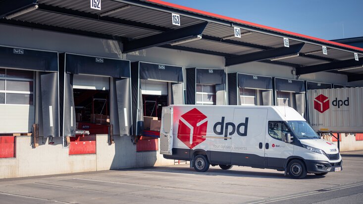 Es steht ein dpd Transporter vor einer Lagerhalle und wird mit Paketen beladen