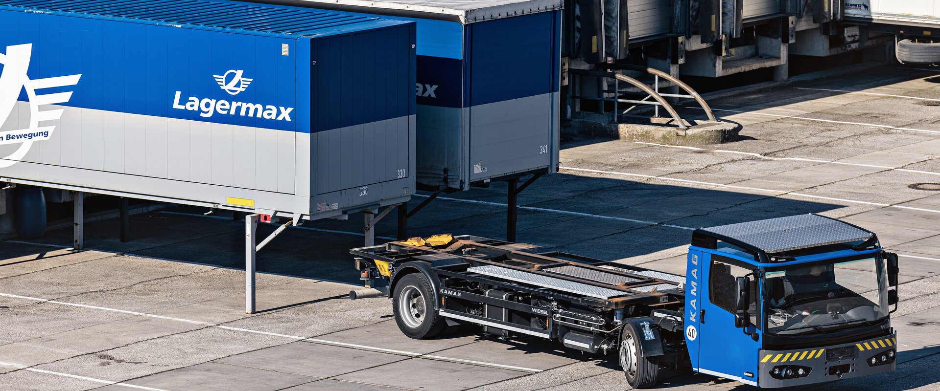 Ein Sattelzug faehrt vor zwei Lasten mit Lagermax Logo