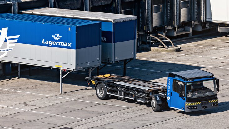 Ein Sattelzug faehrt vor zwei Lasten mit Lagermax Logo