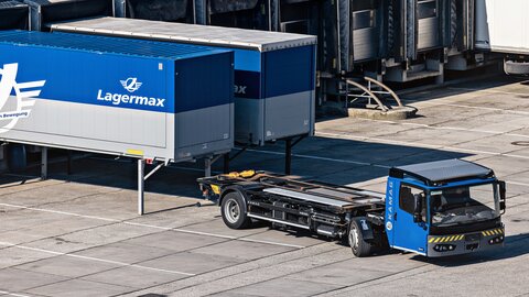 Ein Sattelzug faehrt vor zwei Lasten mit Lagermax Logo