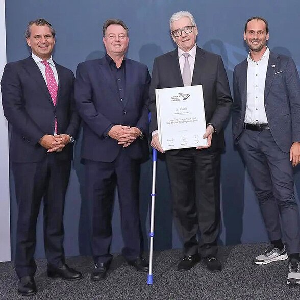 Gruppenbild - Vier Männer mit Urkunde vor blauem Hintergrund