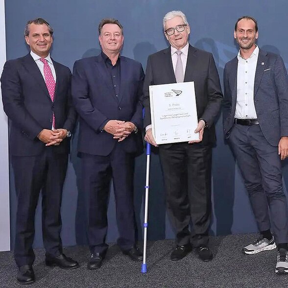 Gruppenbild - Vier Männer mit Urkunde vor blauem Hintergrund