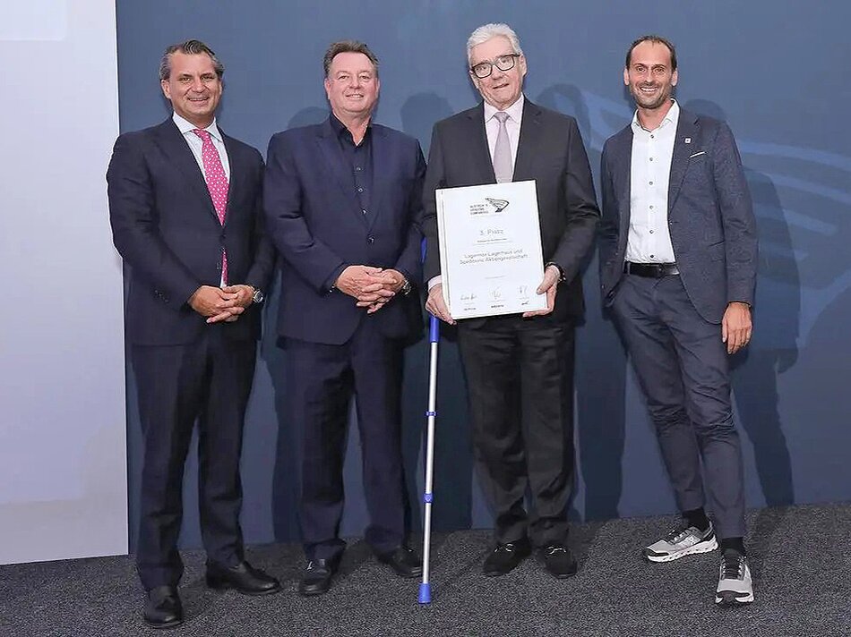 Gruppenbild - Vier Männer mit Urkunde vor blauem Hintergrund