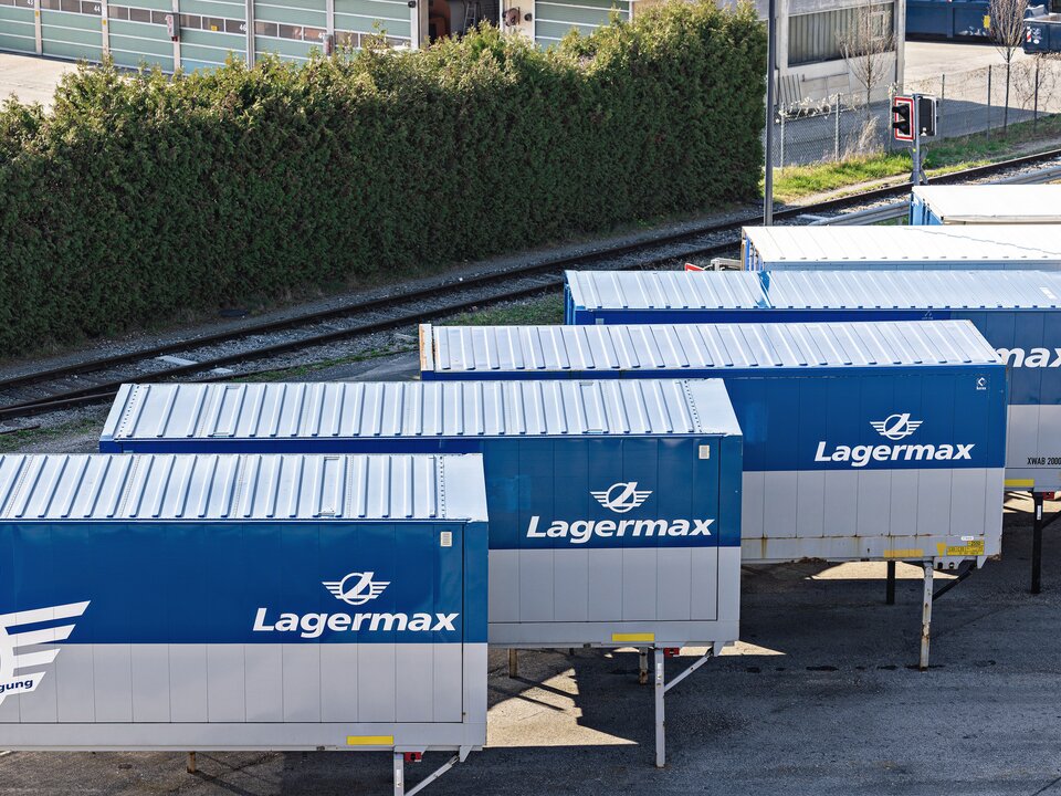 Man sieht mehrere Containeranhaenger in einer Reihe auf einem Parkplatz mit dem Lagermax Logo