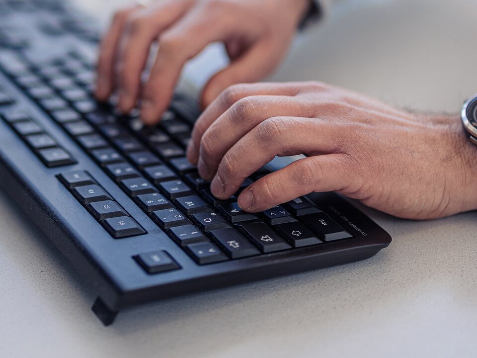 Closeup-Foto von Haenden eines Lagermax-Mitarbeiters an ein einer Computer-Tastatur
