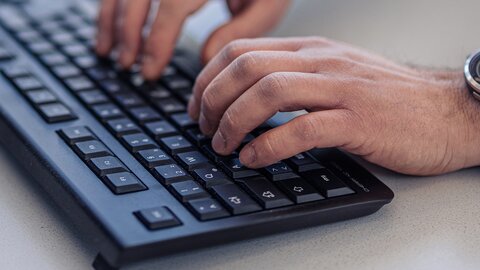 Closeup-Foto von Haenden eines Lagermax-Mitarbeiters an ein einer Computer-Tastatur