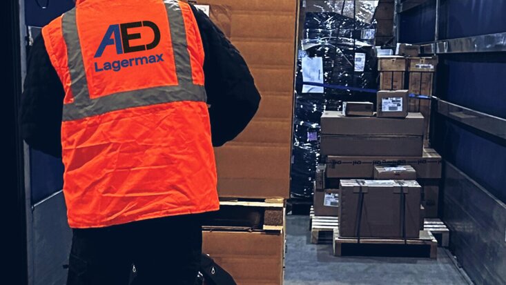 Mann belädt mit Handstapler Lkw mit Kartons von hinten.